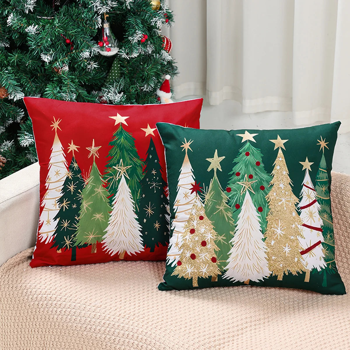 Two Christmas-themed pillows on a couch with a decorated tree in the background.