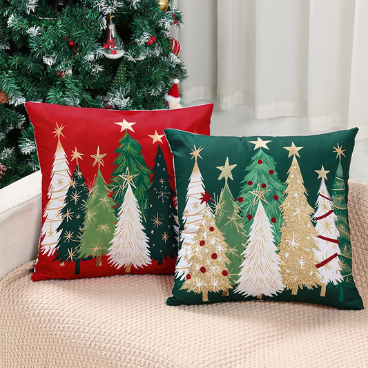 Two Christmas-themed pillows on a couch with a decorated tree in the background.
