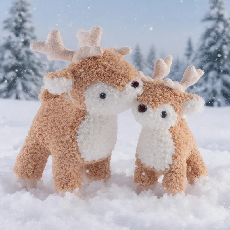 Two plush deer toys in a snowy landscape with trees.