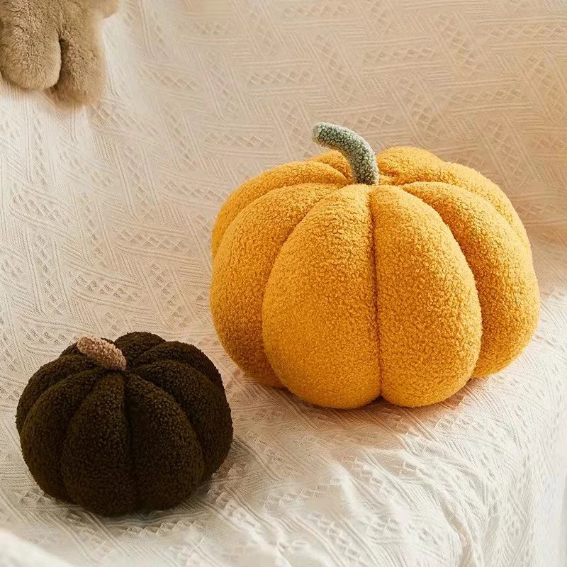 Two textured pumpkin-shaped cushions, one yellow and one brown, on a textured surface.