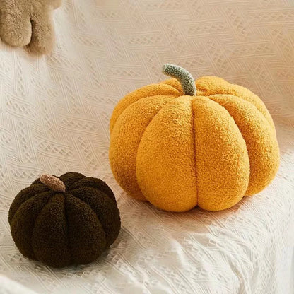 Two textured pumpkin-shaped cushions, one yellow and one brown, on a textured surface.
