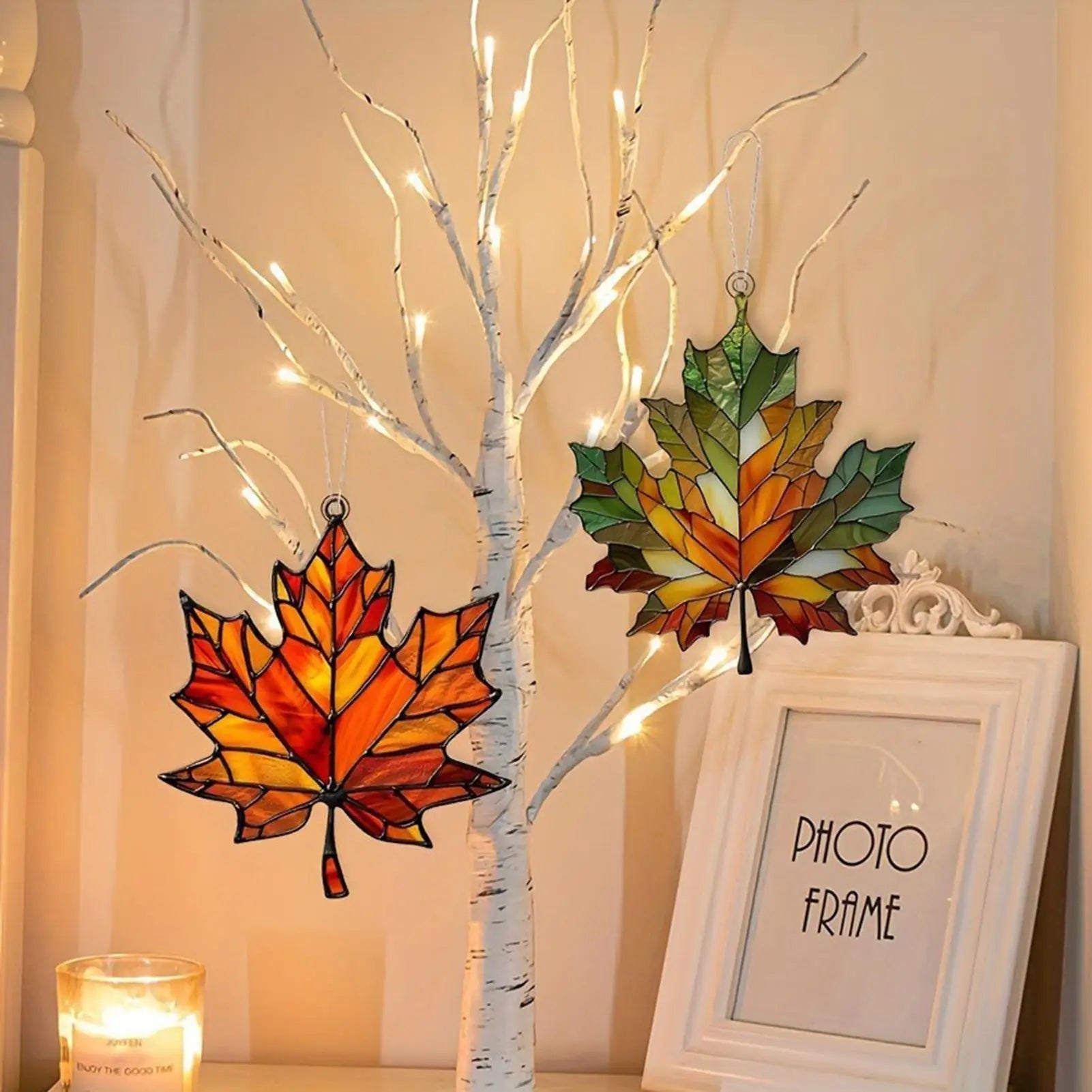 Decorative setup with acrylic leaf ornaments and a photo frame on a neutral background