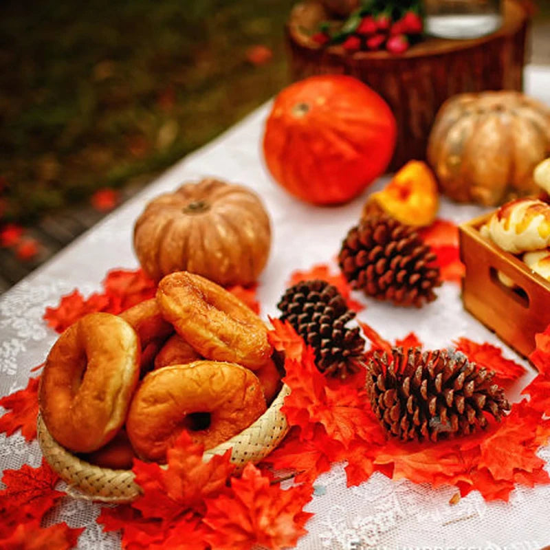 Autumn-themed setting with pumpkins, pinecones, and donuts on a decorative tablecloth.