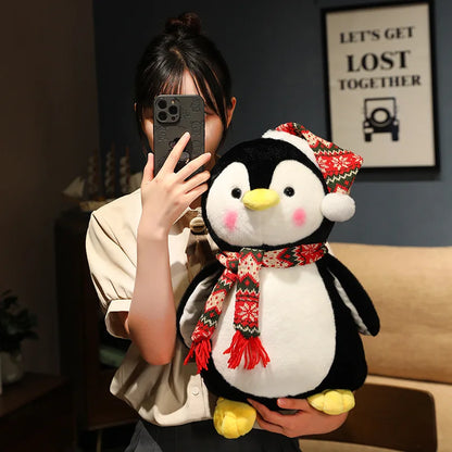 Person holding a plush penguin toy with a red scarf in a room.