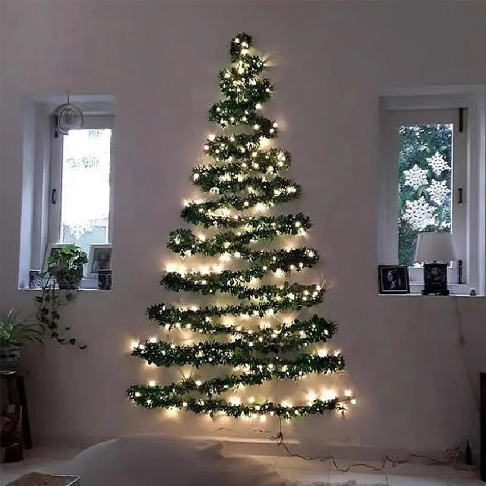 Wall-mounted Christmas tree with lights in a room with windows and plants.