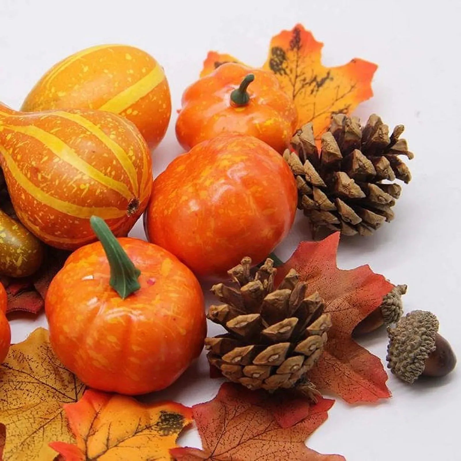Autumn-themed arrangement with pumpkins, gourds, pinecones, and leaves on a white background