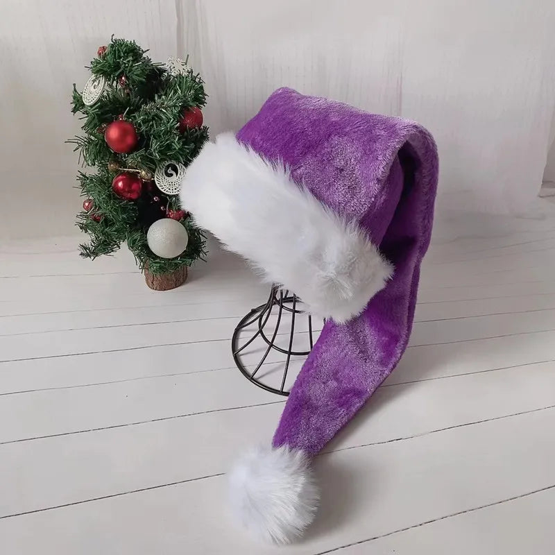 Purple Santa hat with white fur trim on a wooden floor with a small decorated Christmas tree in the background.