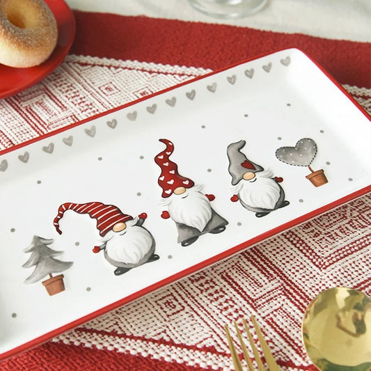 Decorative plate with Christmas-themed gnomes on a red and white patterned tablecloth.