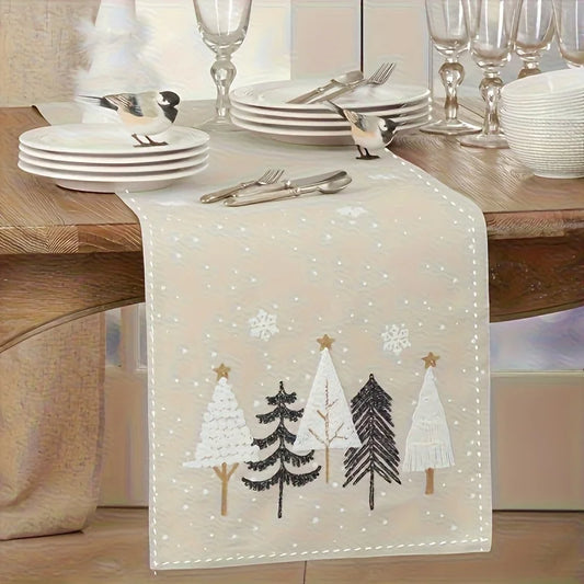 Decorative table runner with embroidered trees on a wooden table.