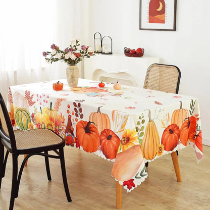 Table with a decorative tablecloth featuring pumpkins and autumn leaves, surrounded by chairs.