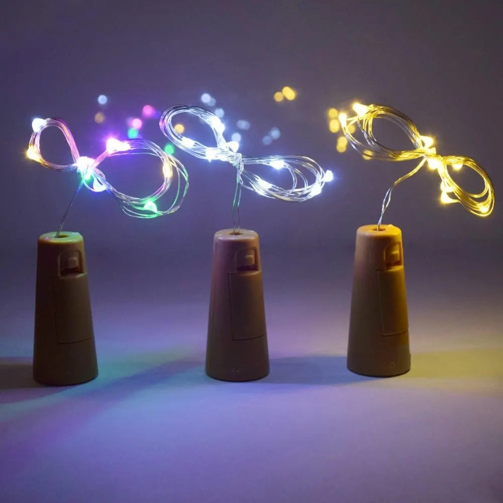 Three wine bottle stoppers with string lights on a dark background