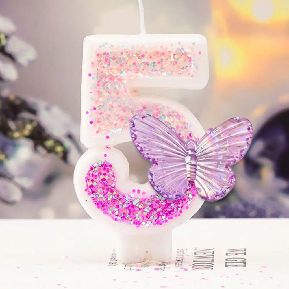Decorative candle shaped like the number '5' with a butterfly and pink glitter on a blurred background