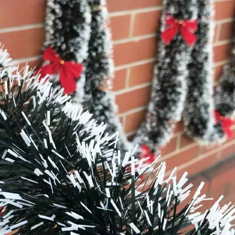 Decorative tinsel with red bows against a brick wall