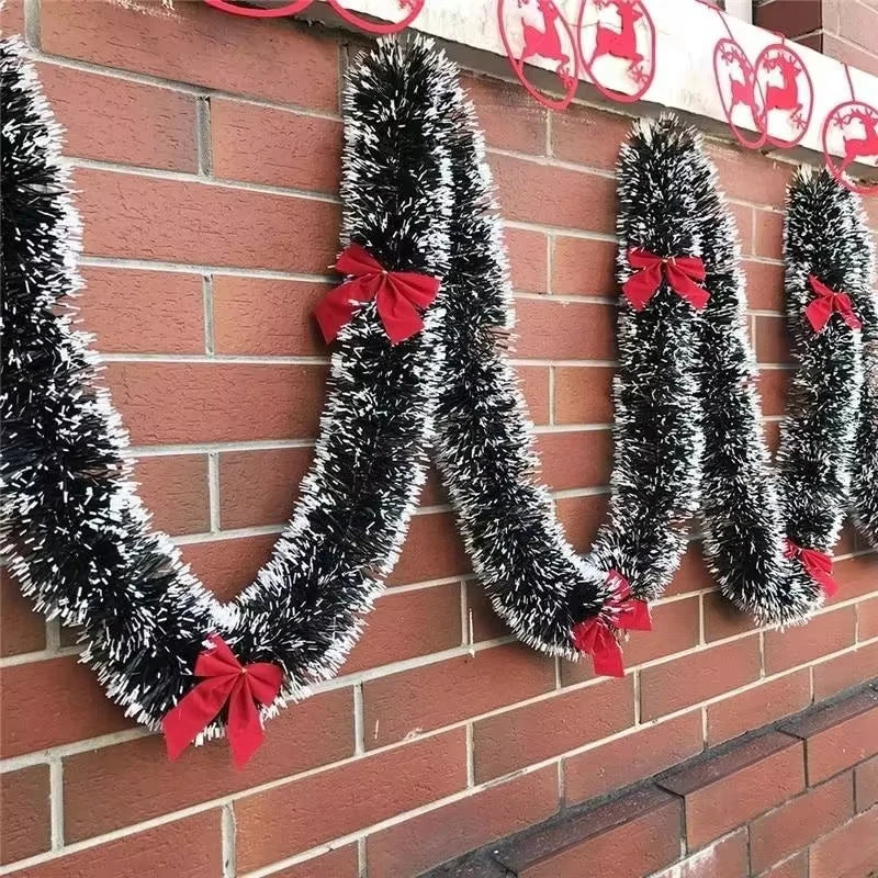 Decorative tinsel garlands with red bows on a brick wall