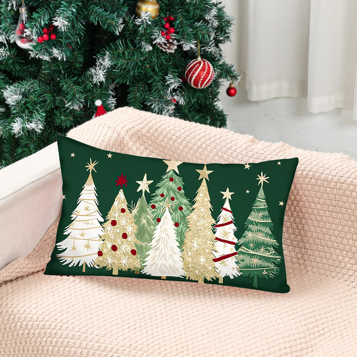 Decorative pillow with Christmas tree design on a couch next to a decorated Christmas tree.