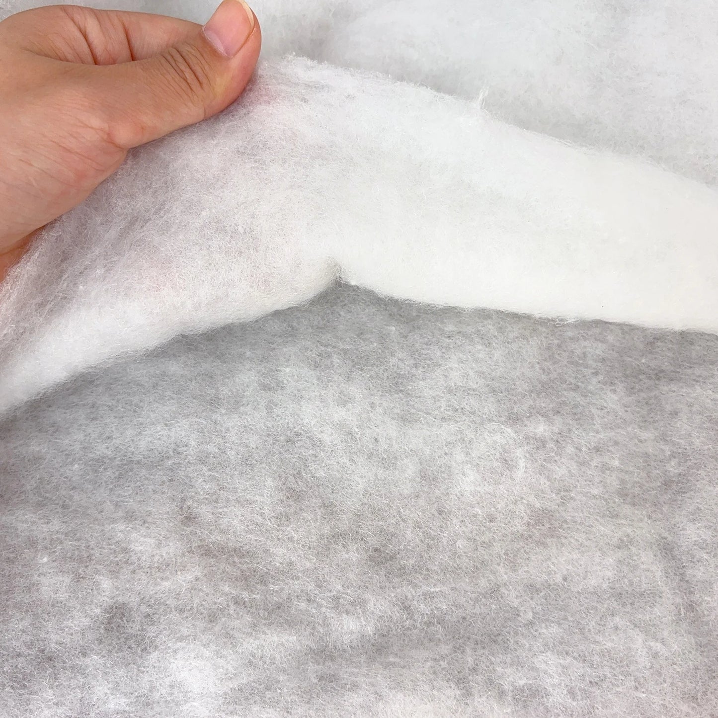 Close-up of gray fabric with a hand touching it, on a white background