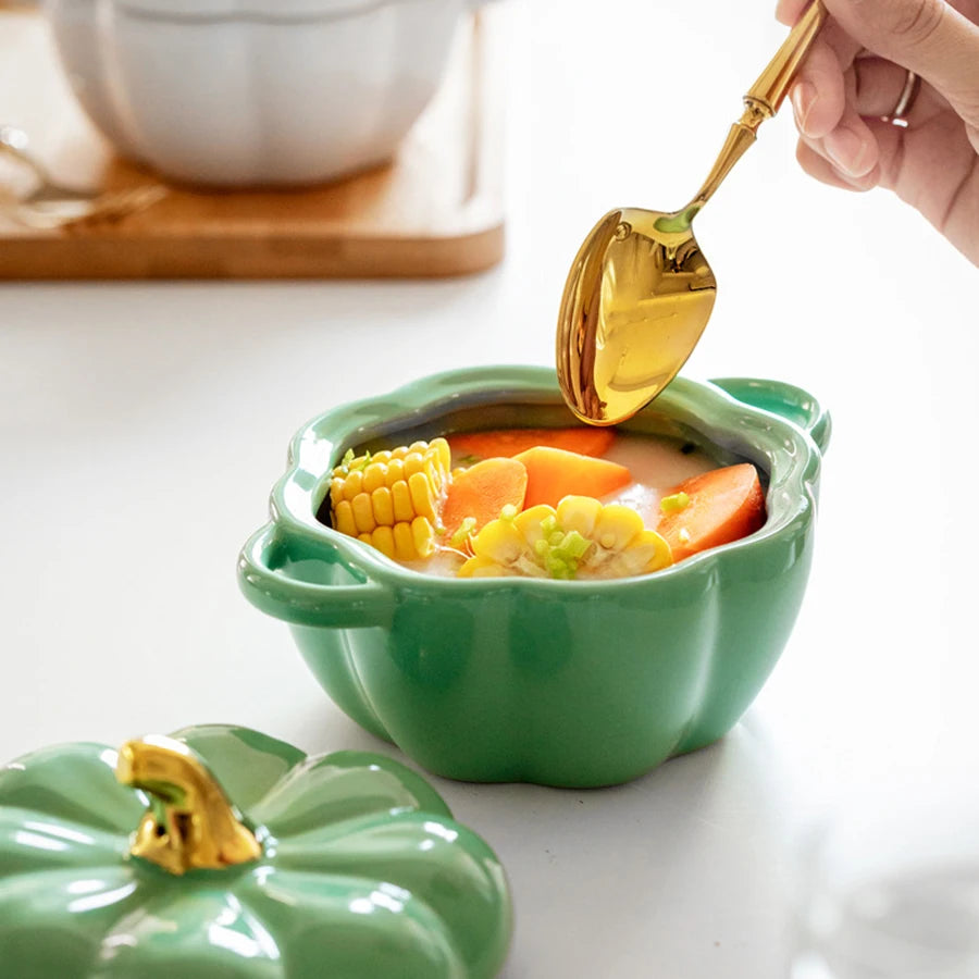 Green pumpkin-shaped bowl with soup and vegetables, being served with a gold spoon.