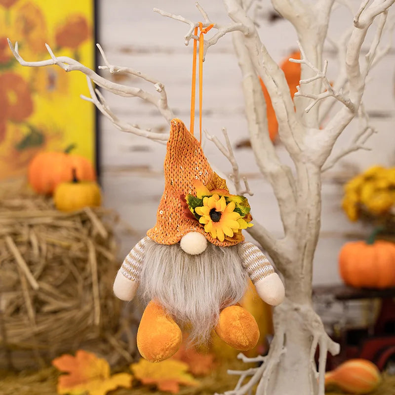 Decorative autumn gnome with sunflower hat hanging from a branch with pumpkins and leaves in the background.