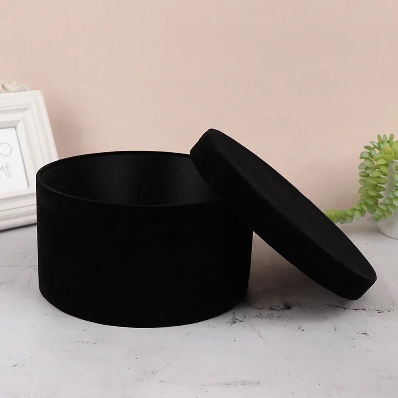 Black round container with lid on a light surface with a neutral background