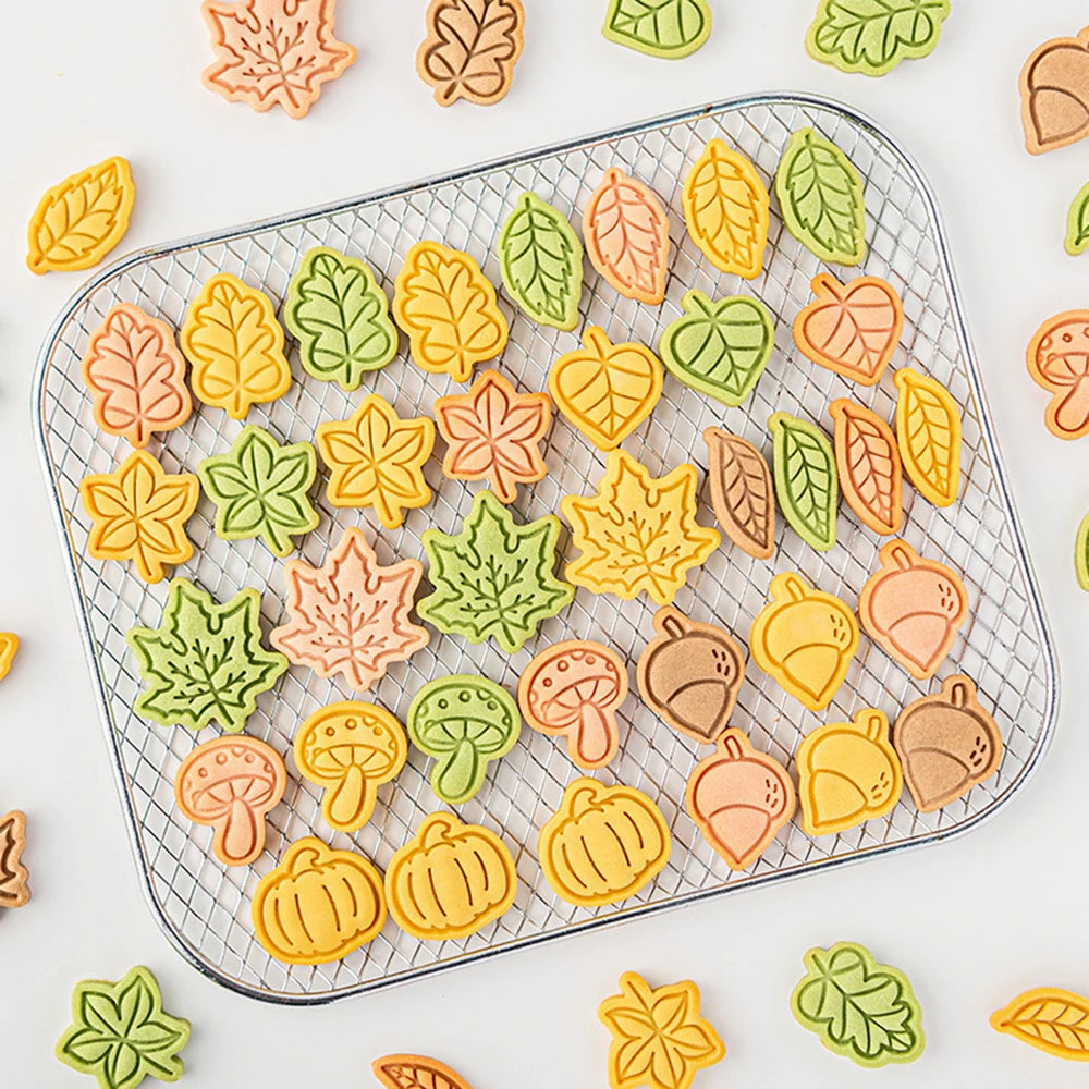 Assorted fall-themed cookies on a cooling rack with colorful leaves and pumpkins.