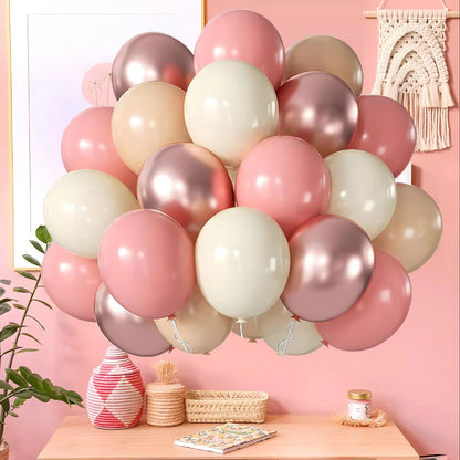 Balloon arrangement in pink, white, and gold on a table with a pink wall background.