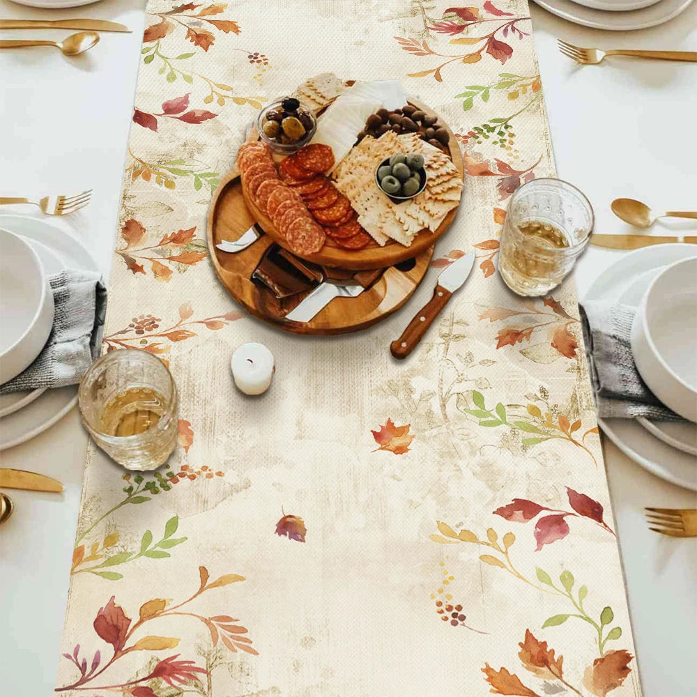 Dining table setting with a fall-themed tablecloth, appetizers, and glasses.