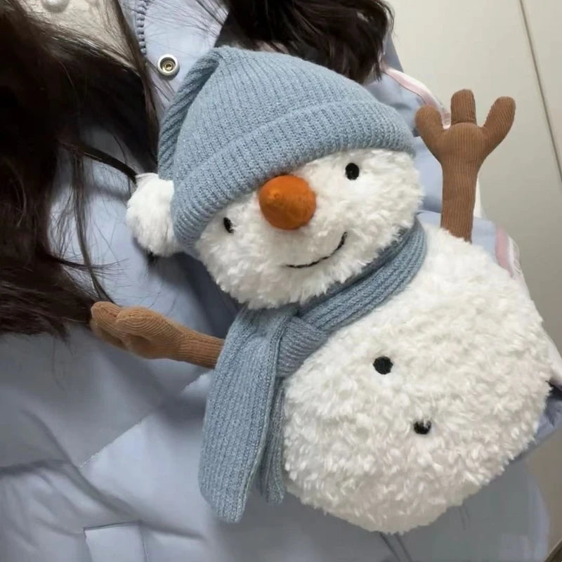 Stuffed snowman toy with a blue hat and scarf held by a person
