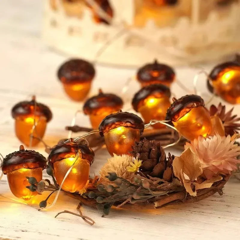 Decorative string lights shaped like acorns on a wreath with flowers and pinecones.
