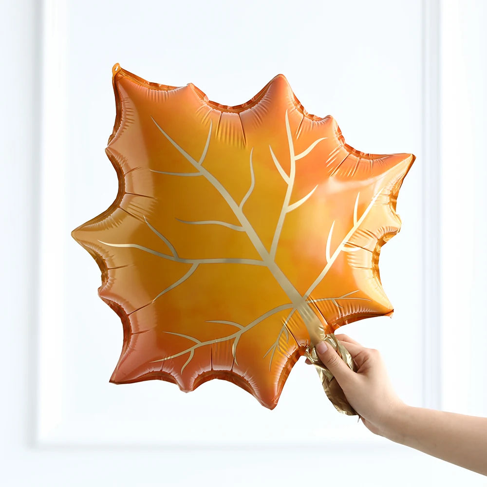 Hand holding a large orange leaf-shaped balloon against a white background