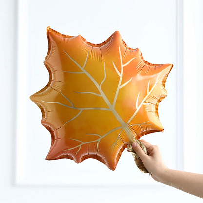 Hand holding a large orange leaf-shaped balloon against a white background