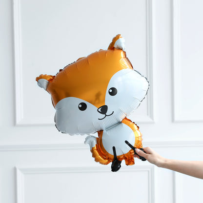 Hand holding a cartoonish fox-shaped balloon against a white paneled wall.