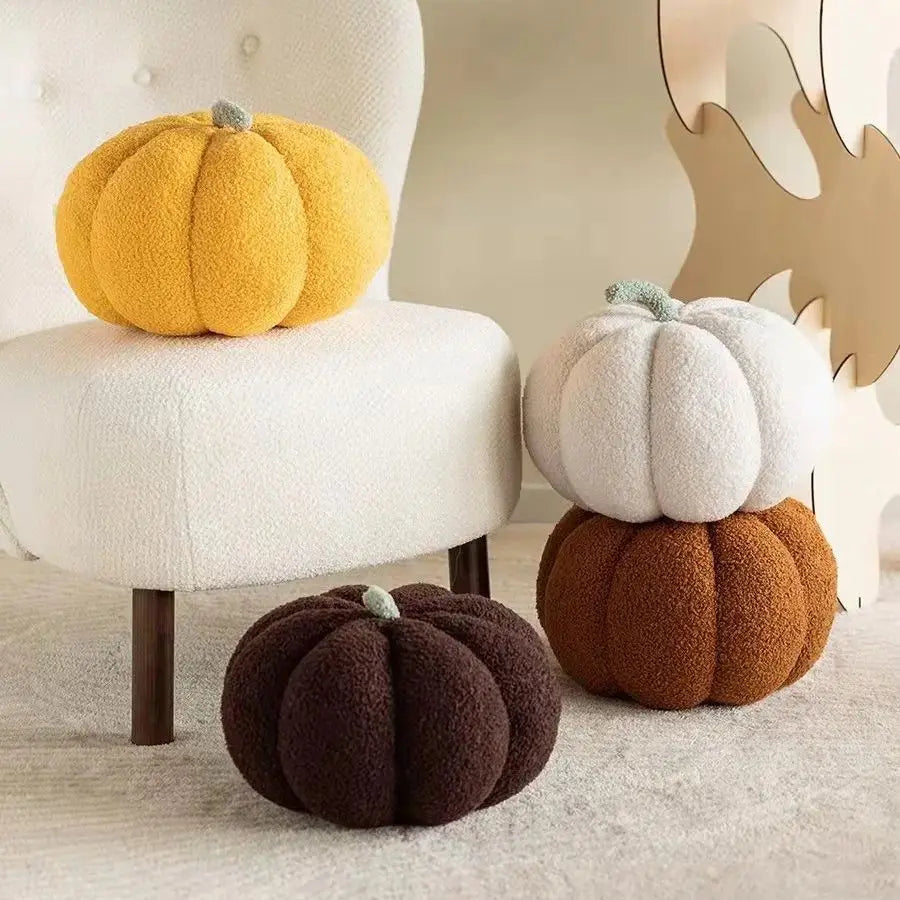 Four textured pumpkin-shaped cushions in yellow, white, brown, and black on a neutral background.
