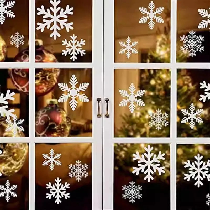 White snowflake window decals on a glass door with Christmas decorations inside.