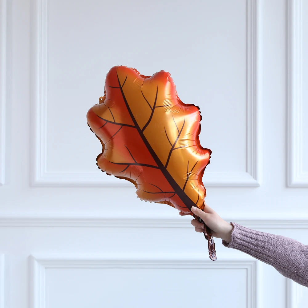 Hand holding a leaf-shaped balloon against a white paneled wall