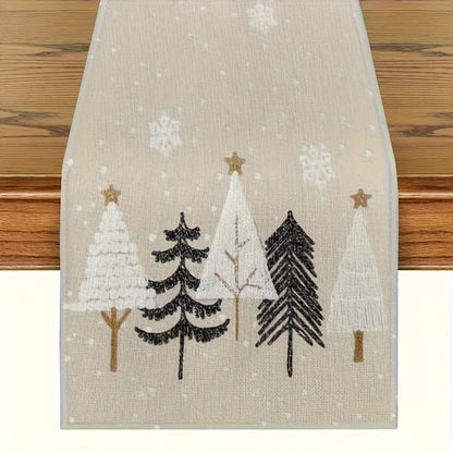 Decorative table runner with embroidered trees and snowflakes on a wooden surface