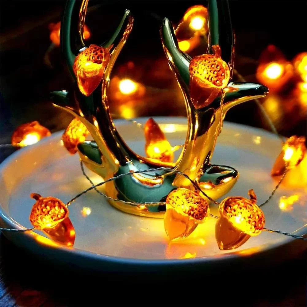 Decorative string lights shaped like acorns and branches on a white plate with a blurred warm light background.