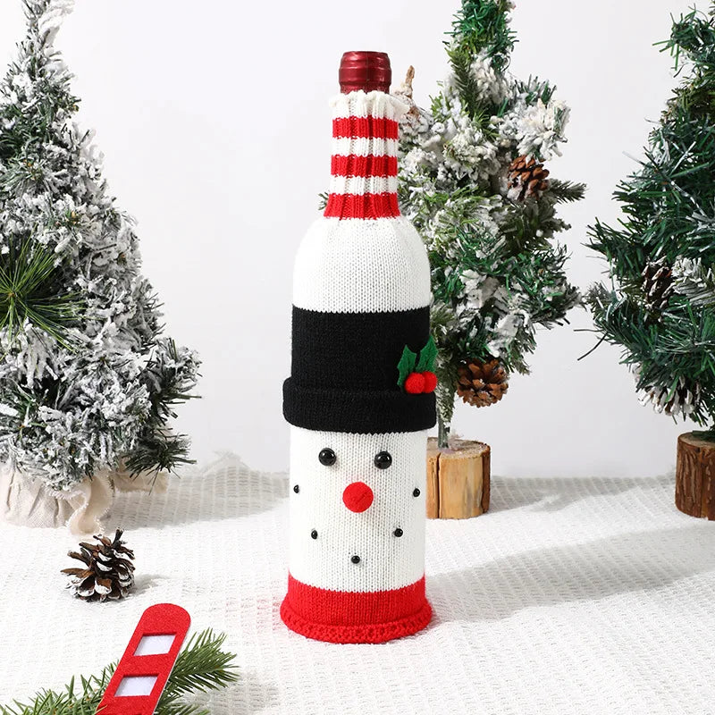 Knitted snowman bottle cover on a wine bottle with Christmas decorations in the background.
