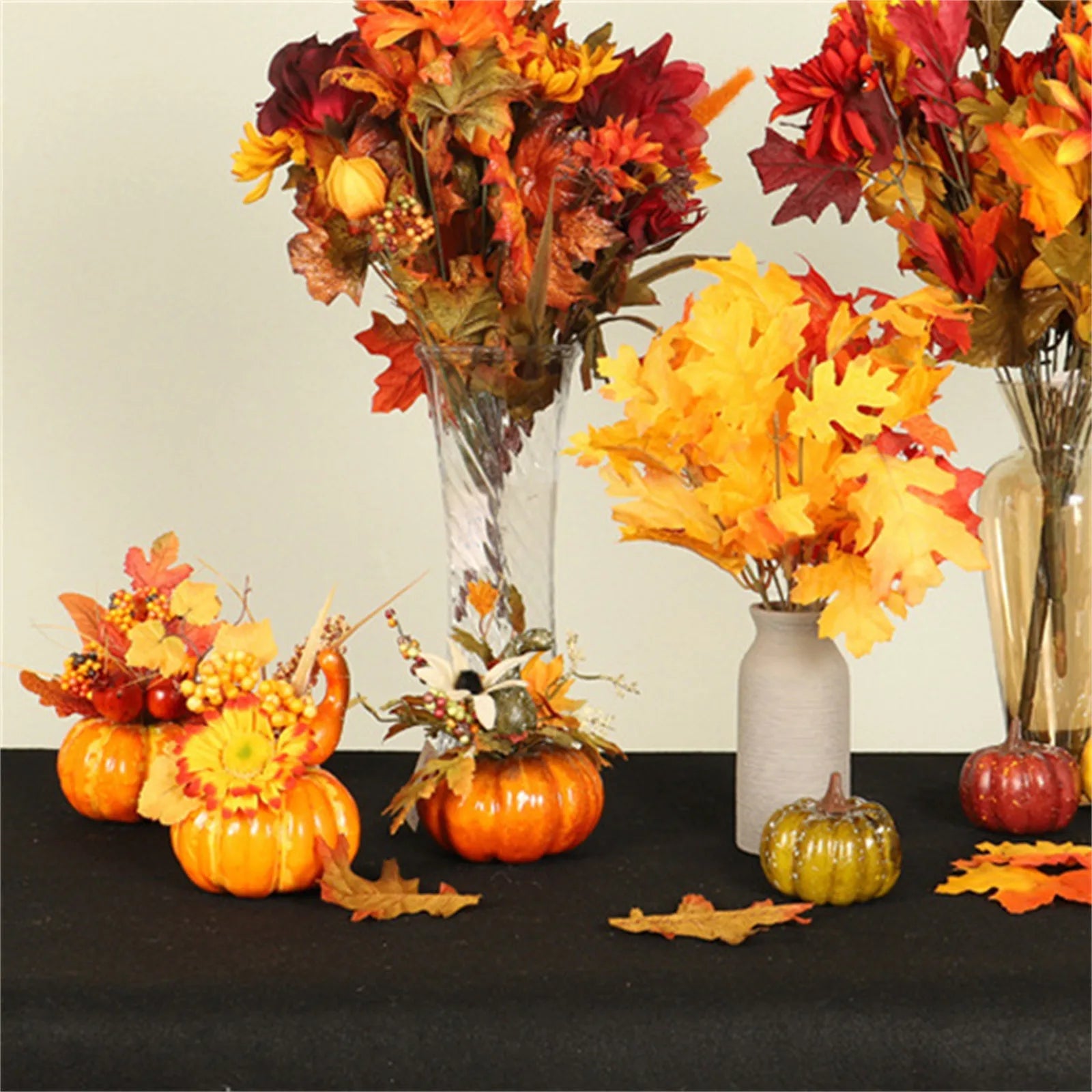 Autumn-themed decorations including pumpkins, leaves, and flowers on a black surface.