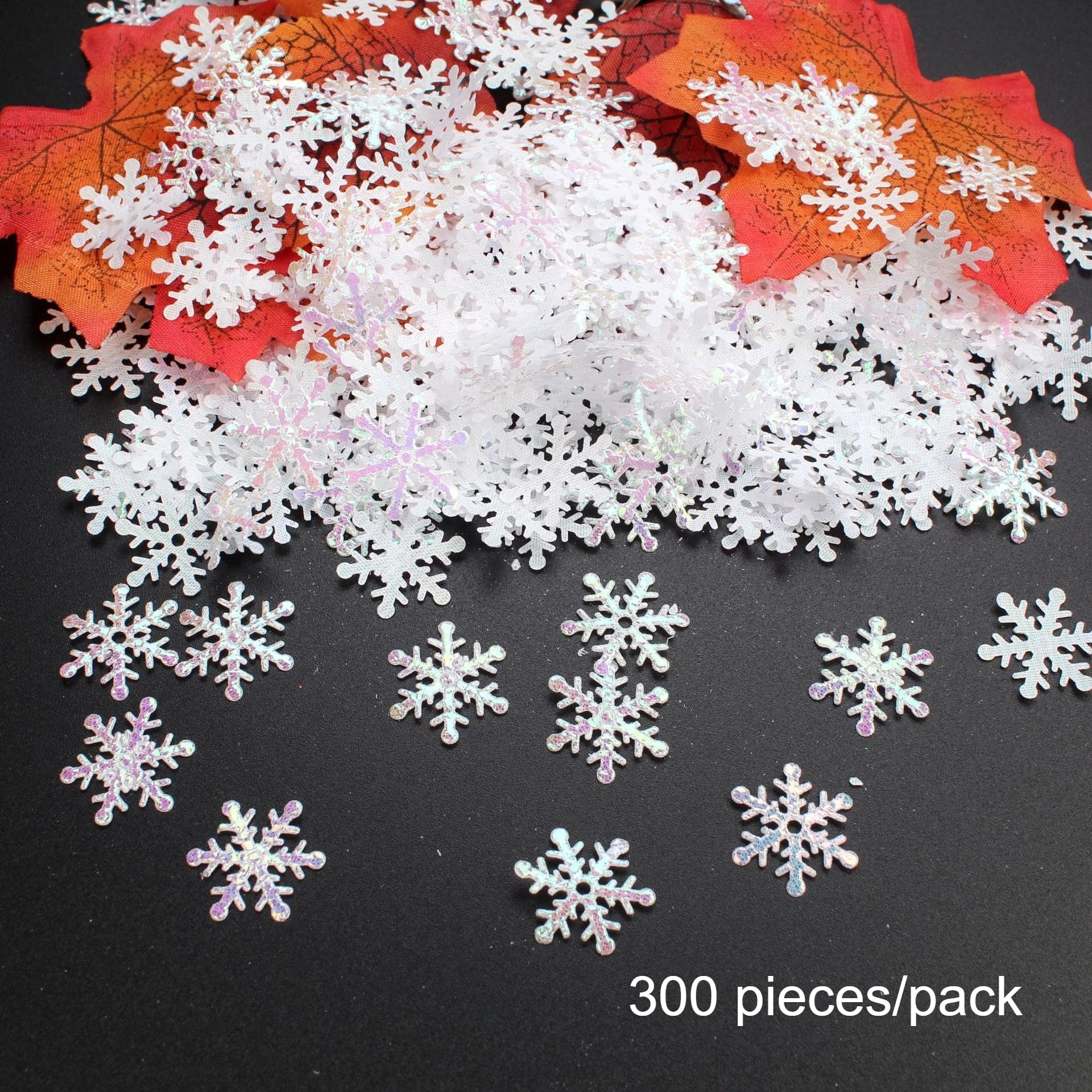 White snowflake-shaped decorations on a black surface with red and orange leaves.