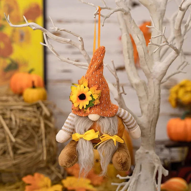 Decorative gnome with sunflower hat hanging from a branch with pumpkins and hay bale in the background.