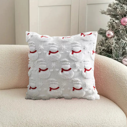 Decorative pillow with red snowman pattern on a beige couch next to a Christmas tree.
