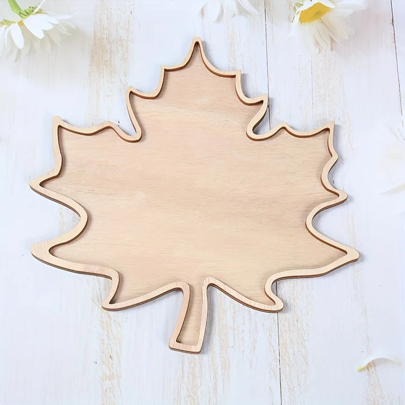 Wooden leaf-shaped cutting board on a light wooden surface with white flowers.