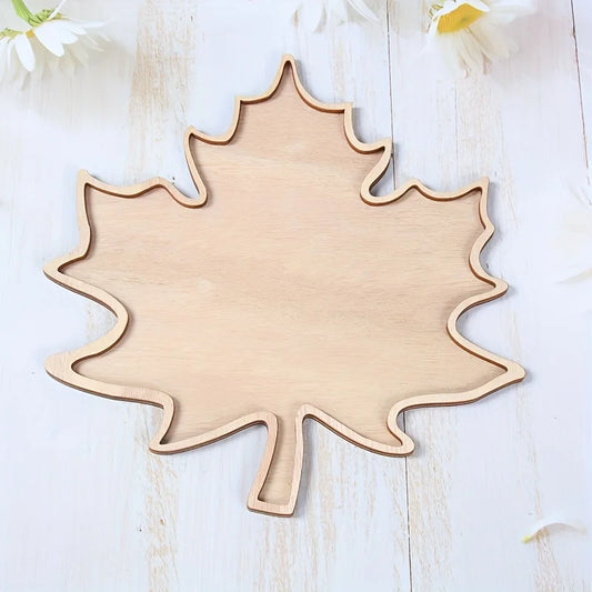 Wooden leaf-shaped cutting board on a light wooden surface with white flowers.
