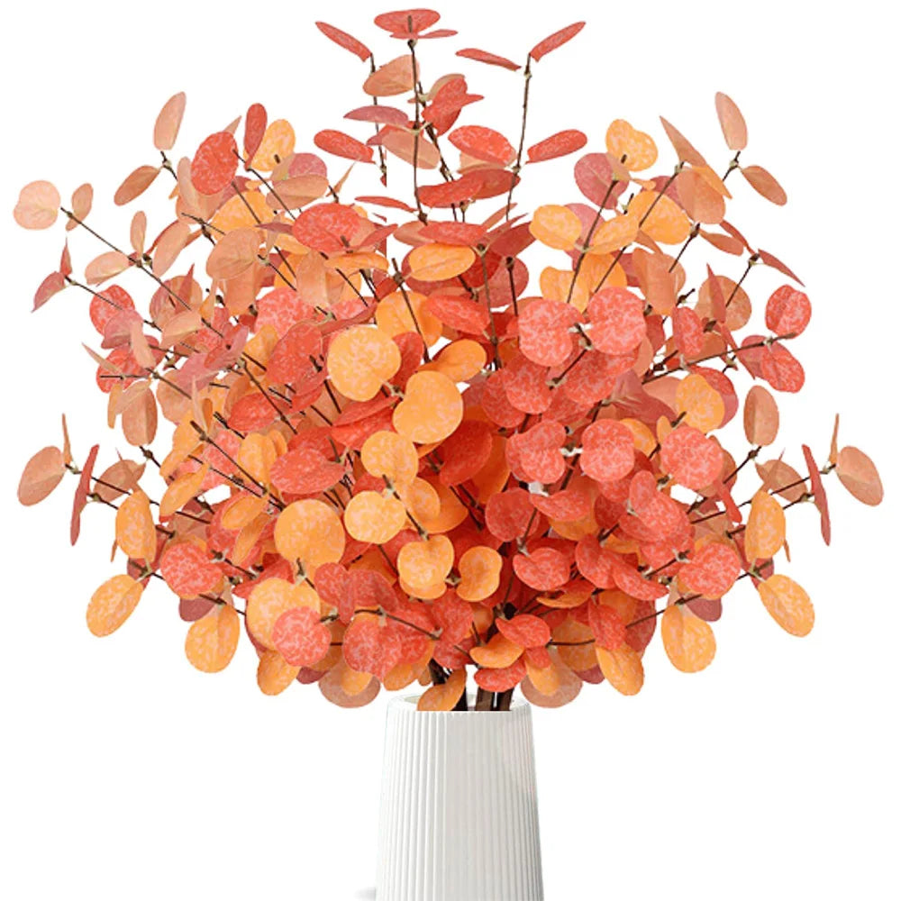 Artificial orange and red leaf branch in a white vase on a white background