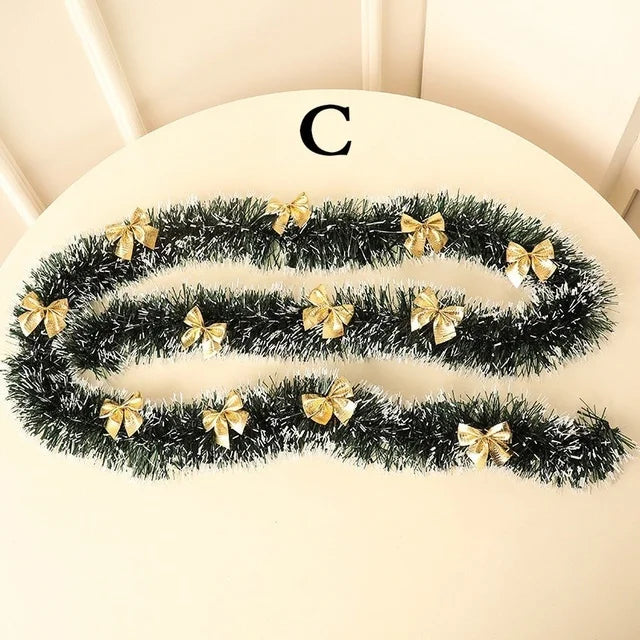 Black tinsel garland with gold bows on a beige surface