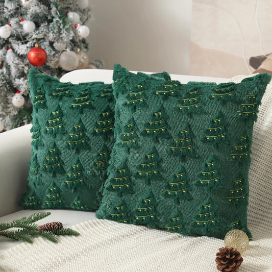 Green textured pillows with Christmas tree pattern on a couch with a decorated tree in the background.