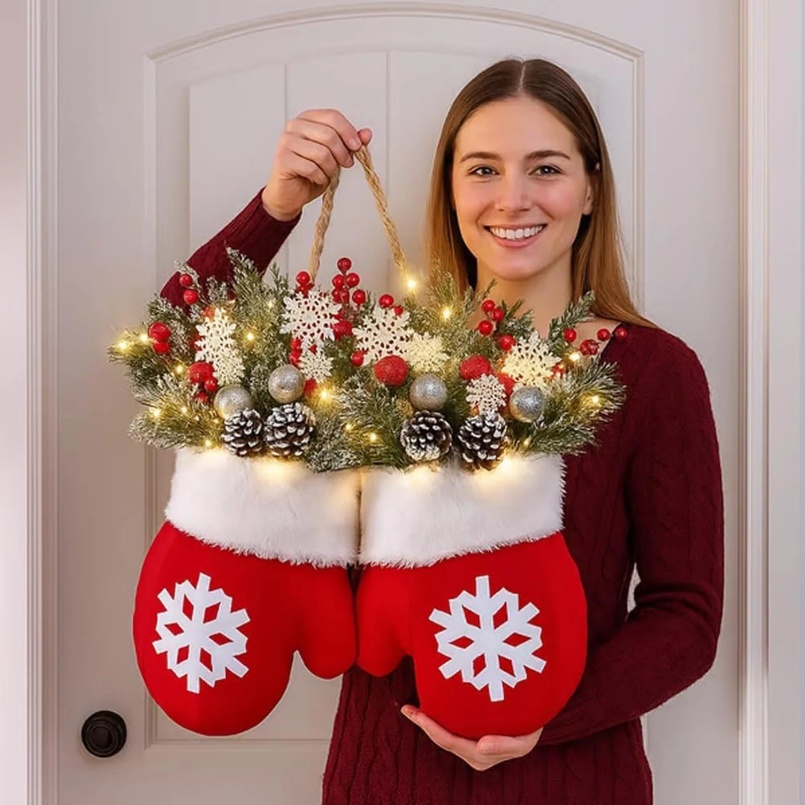 Person holding a decorative item shaped like red mittens with white snowflakes, filled with Christmas lights and ornaments.