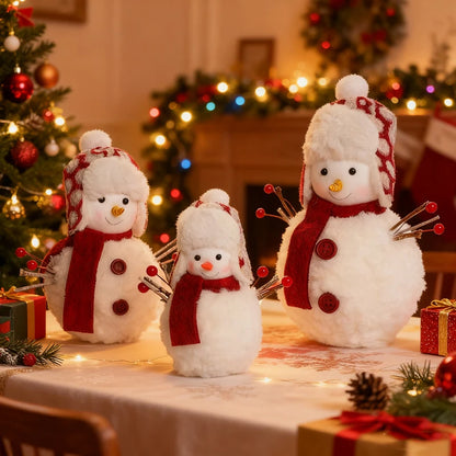 Three snowman decorations on a table with a Christmas tree and wreath in the background.