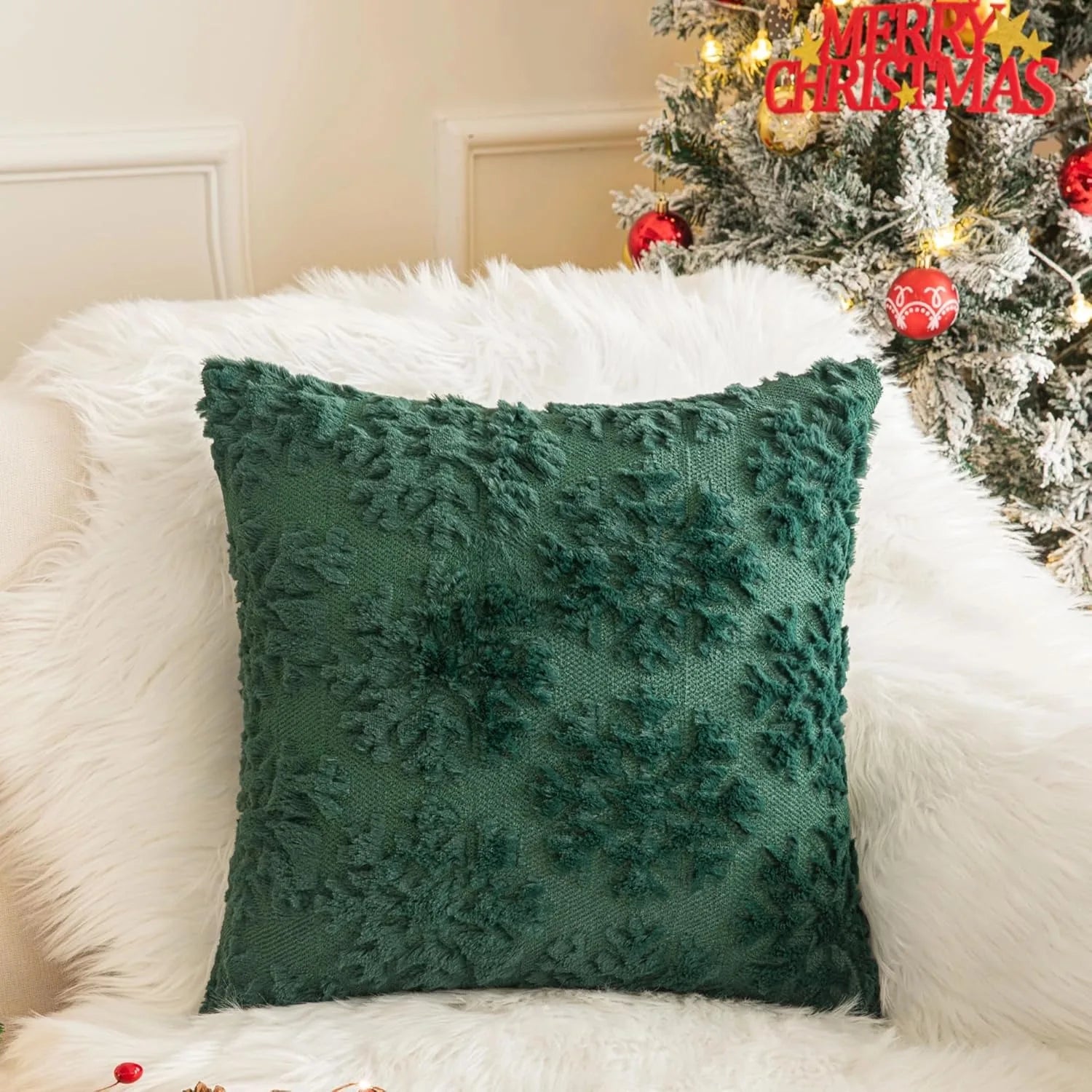 Green textured pillow on a white couch with a Christmas tree in the background