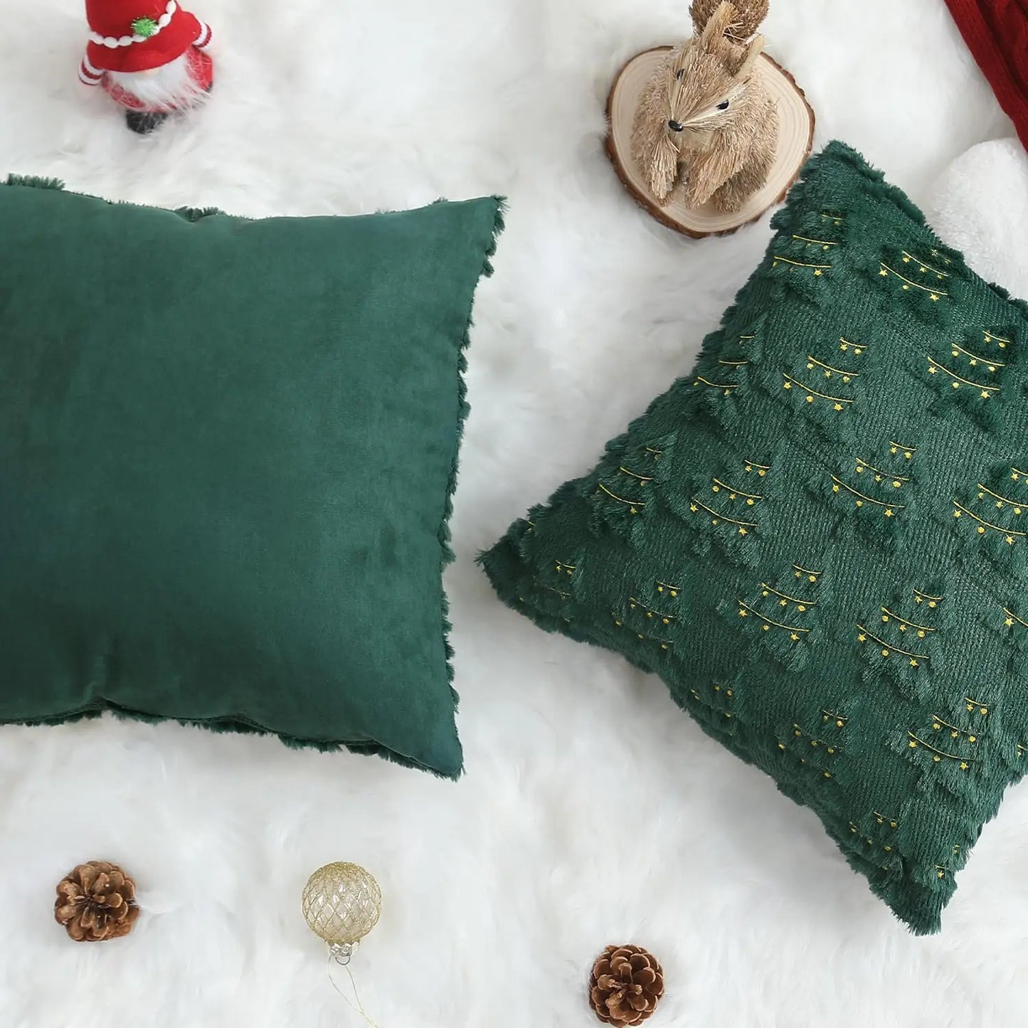 Two green pillows on a snowy surface with Christmas decorations.